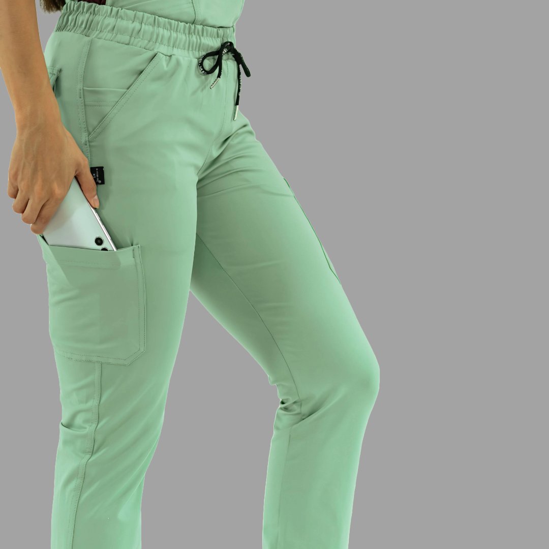 Detalle lateral de pantalón médico 930 verde menta con mano en bolsillo guardando celular.