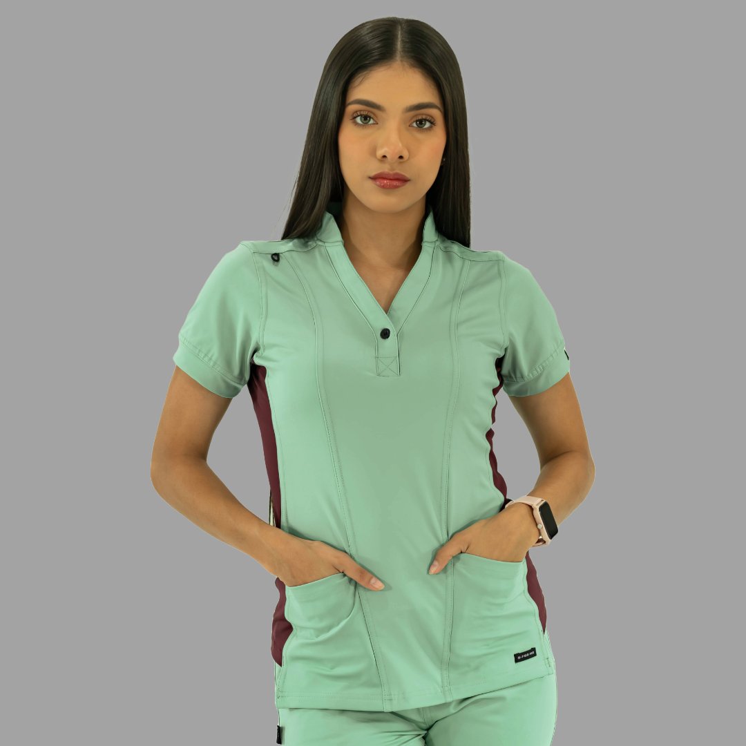 Vista frontal de filipina médica verde menta con detalles vino y manos en bolsillos.