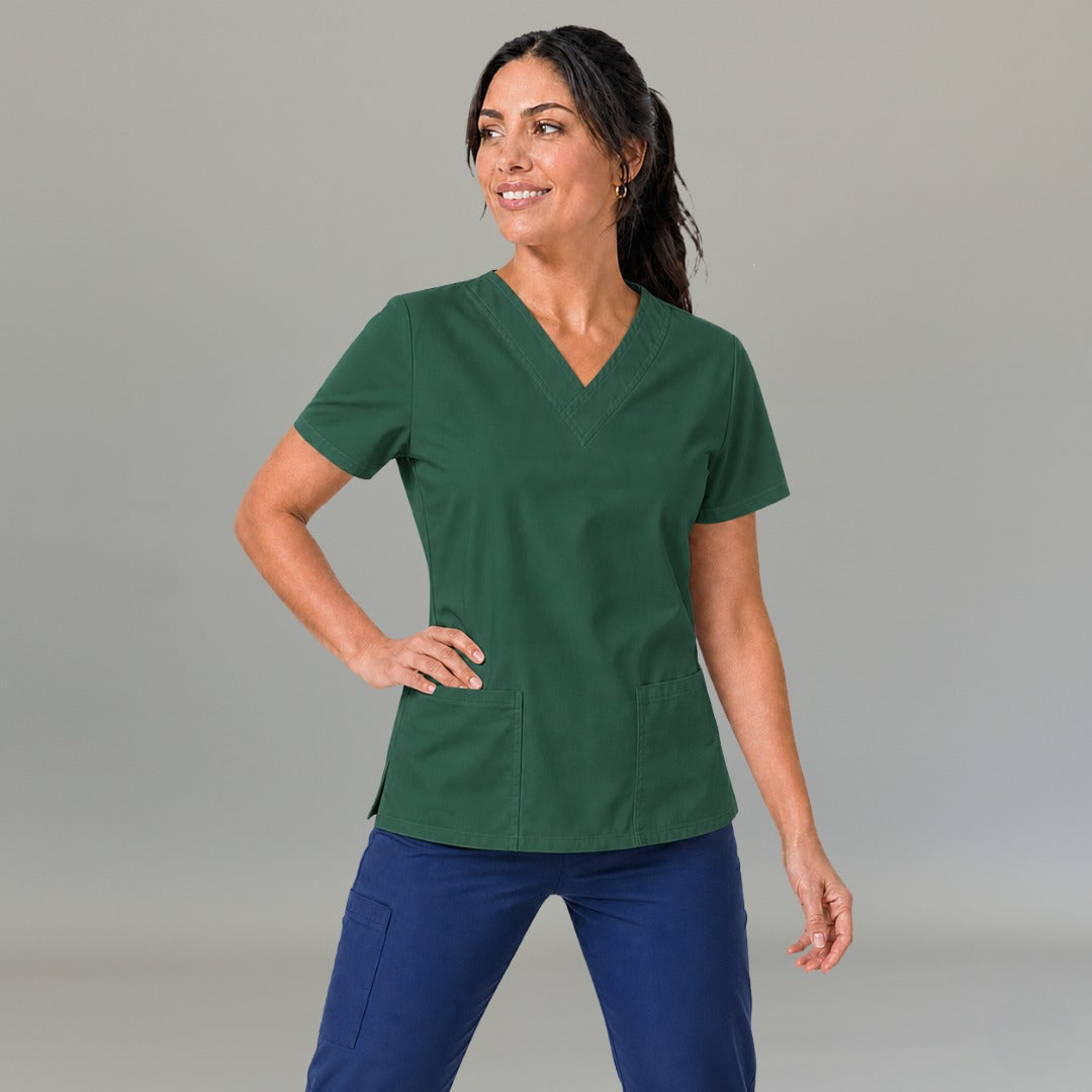Modelo luciendo la filipina quirúrgica verde botella 502 para mujer, combinada con pantalones azules.