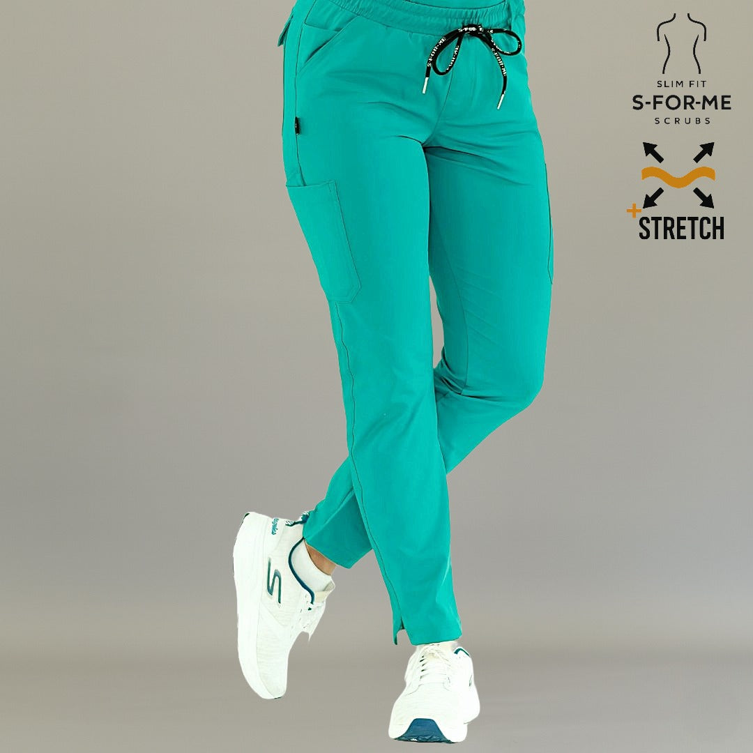 Vista en tres cuartos de pantalón médico 930 color teal con las piernas cruzadas.
